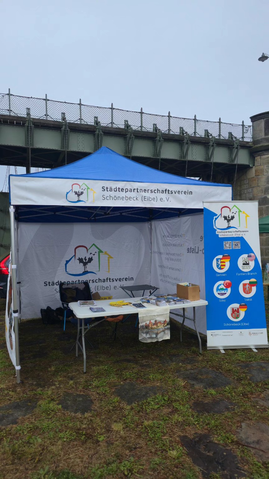Informationsstand des Städtepartnerschaftsvereins mit blauem Pavillon und Roll-up am Pretziener Wehr